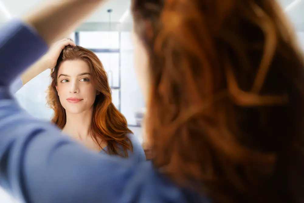 Mujer observando su cabello sano en el espejo